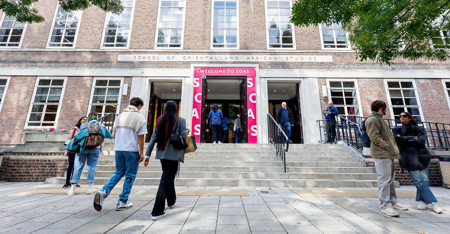 Students and visitors walking outside the SOAS building, with the entrance stairs visible.